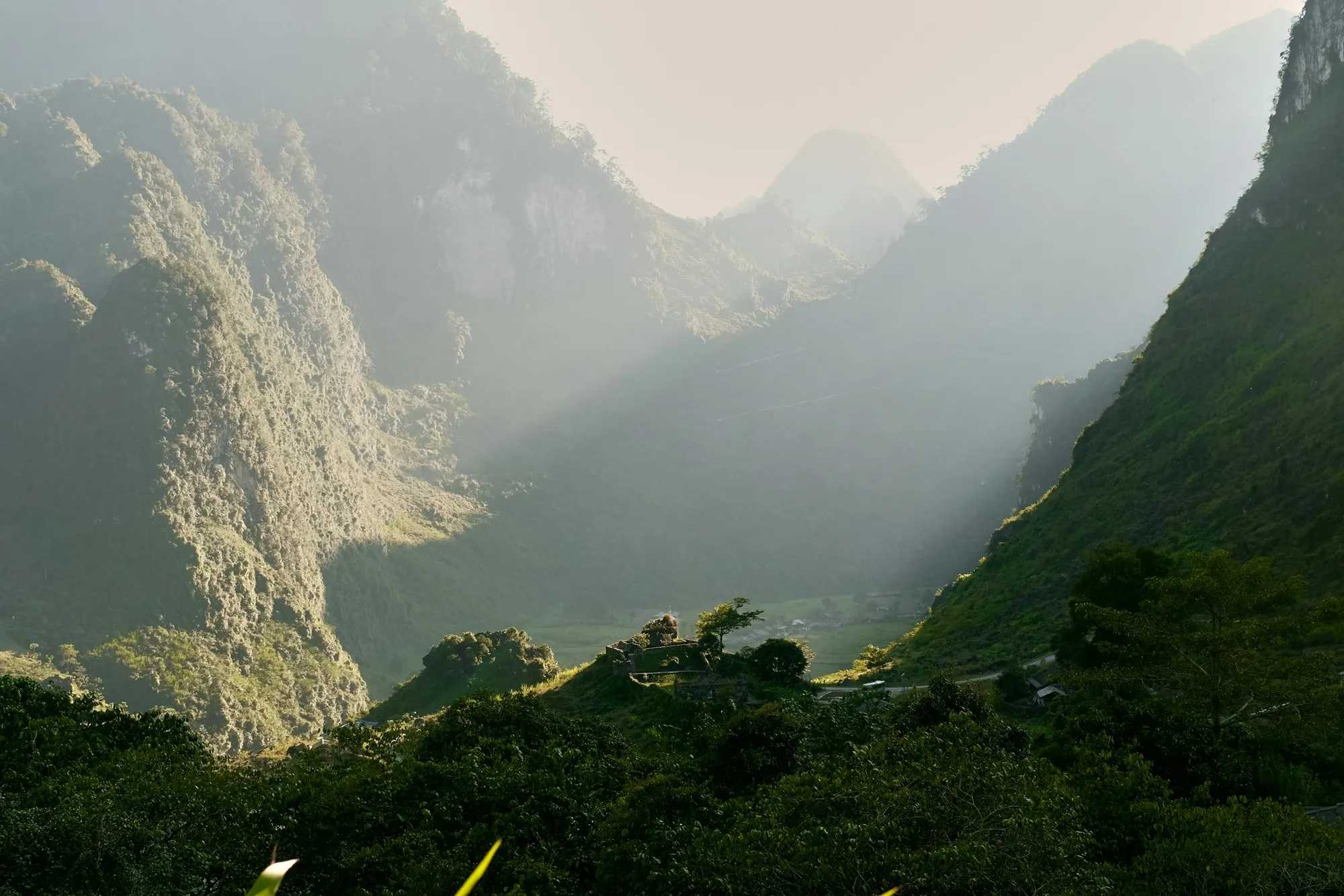 Sunlight streaming into a misty mountain valley near Yen Minh
