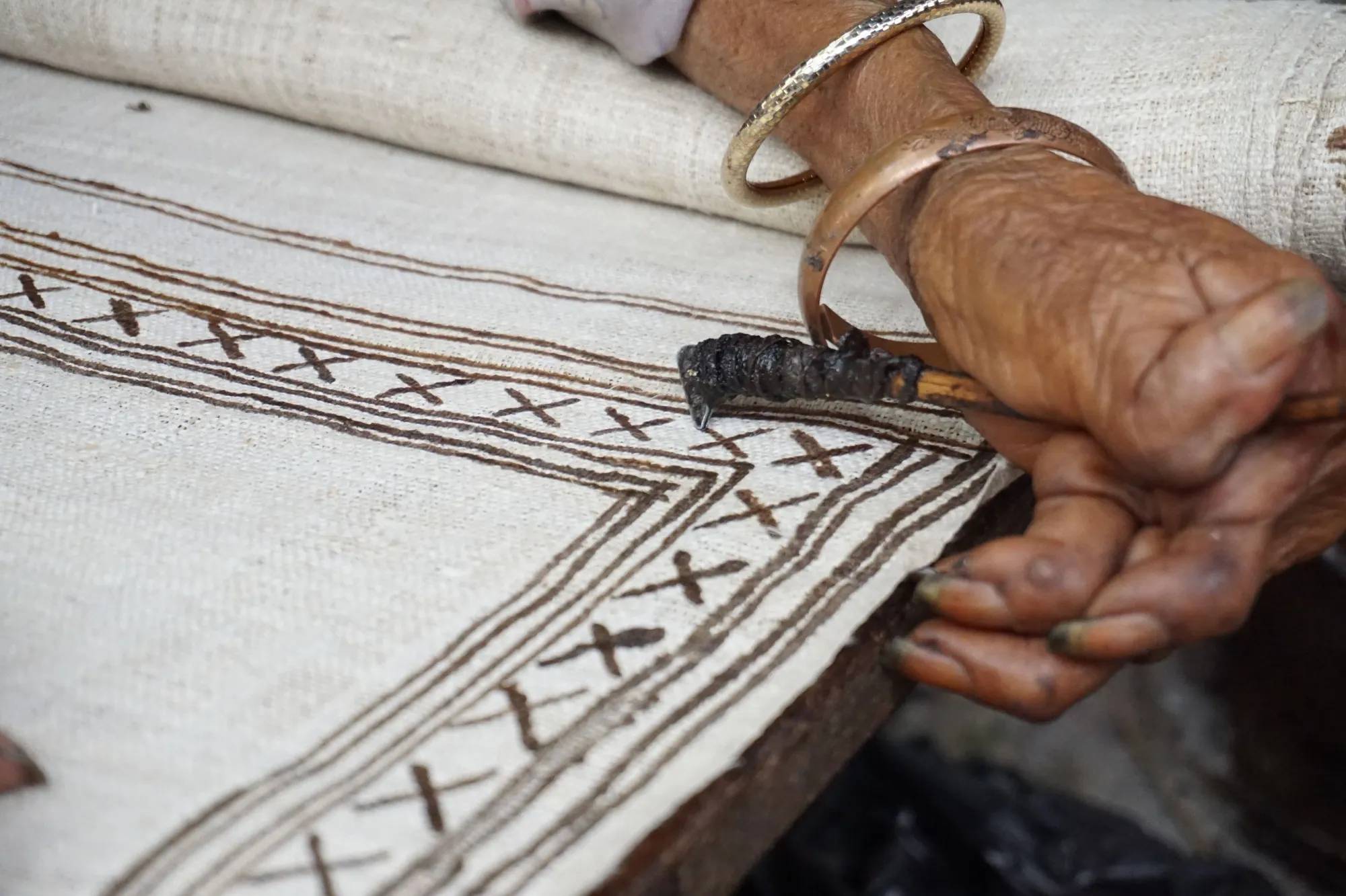 Hands drawing a pattern on hemp linen