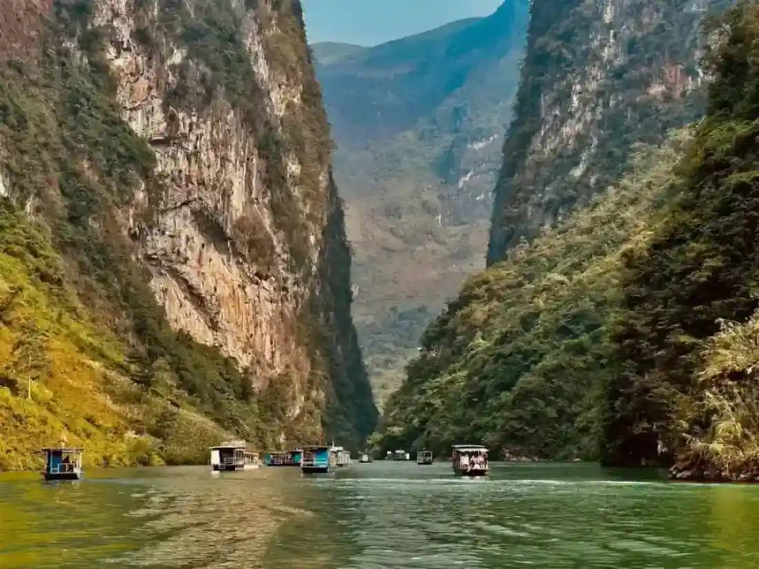 Boats on the green river between steep canyon walls